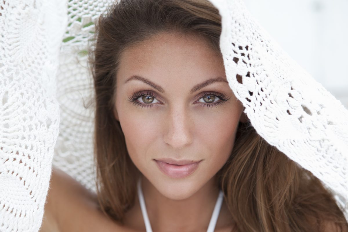 Beautiful Brunette Peeking Out from White Lace Sheet