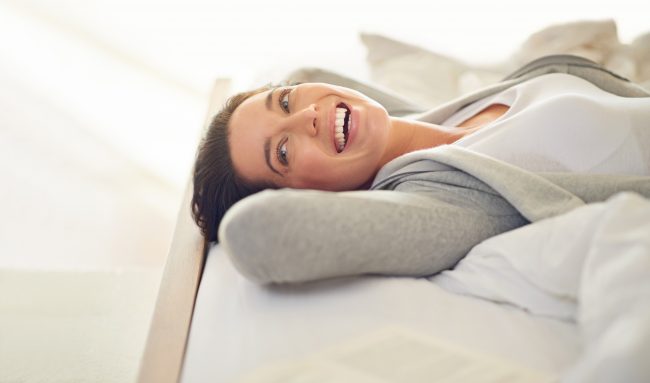 Smiling woman lying on her bed (model)