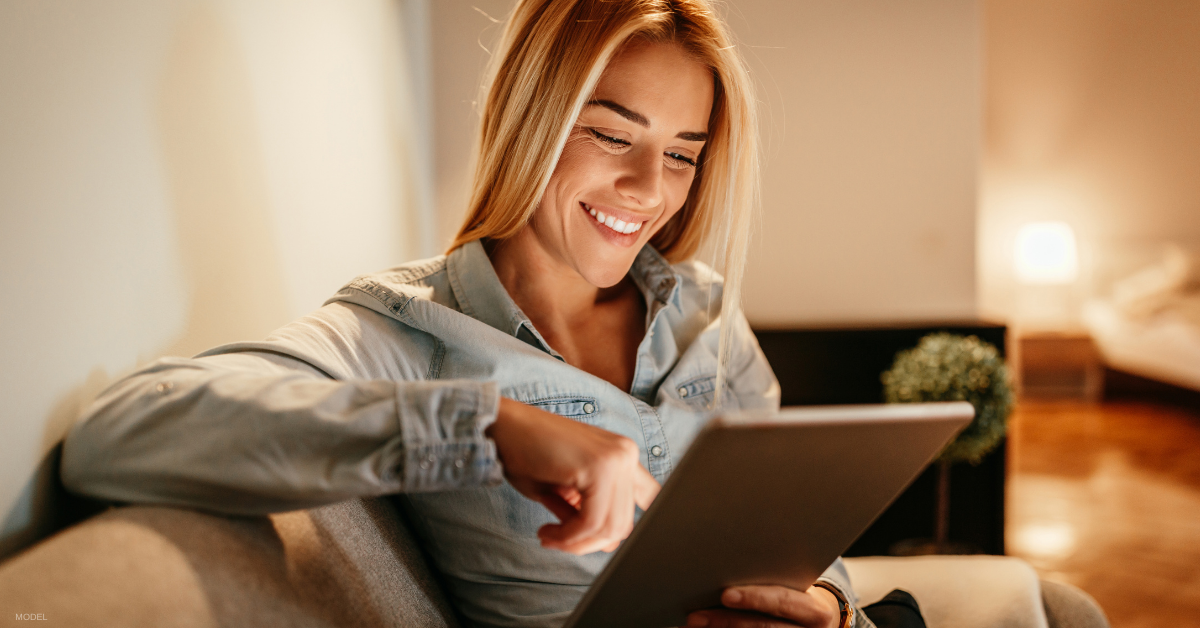 Woman in looking at before-and-after photos of breast augmentation online (model)