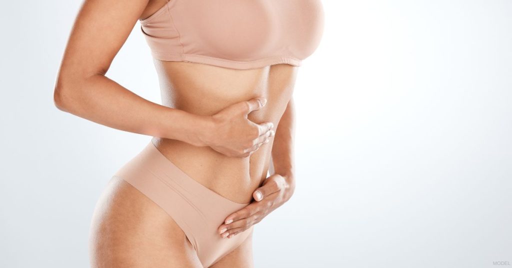 A woman with their hands on their stomach. (Model)