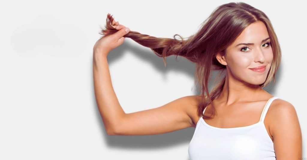 Woman in a white tank top is brushing their hair (model)