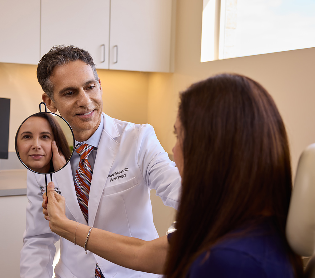Dr. Michael Newman consulting with a patient holding a mirror.
